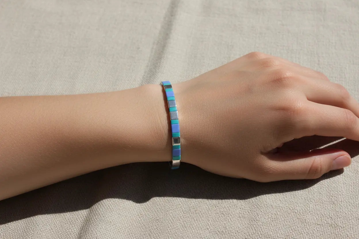 Azure Pulse Tila Bracelet by Gem N Glow features vibrant blue Miyuki beads woven into an intricate, stylish jewelry piece.