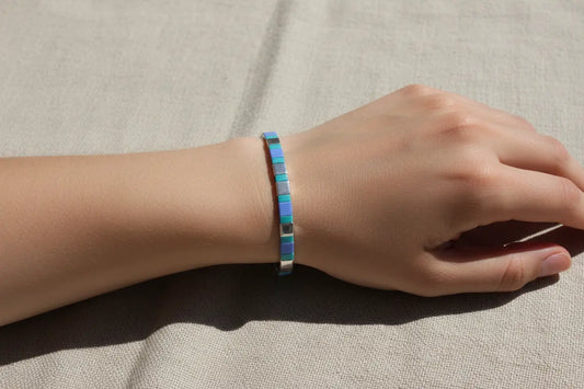 Azure Pulse Tila Bracelet by Gem N Glow features vibrant blue Miyuki beads woven into an intricate, stylish jewelry piece.