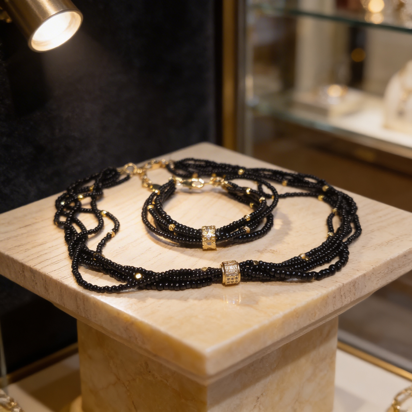 Black onyx layered bracelet with gold textured centerpiece on marble display, minimalist luxury jewelry
